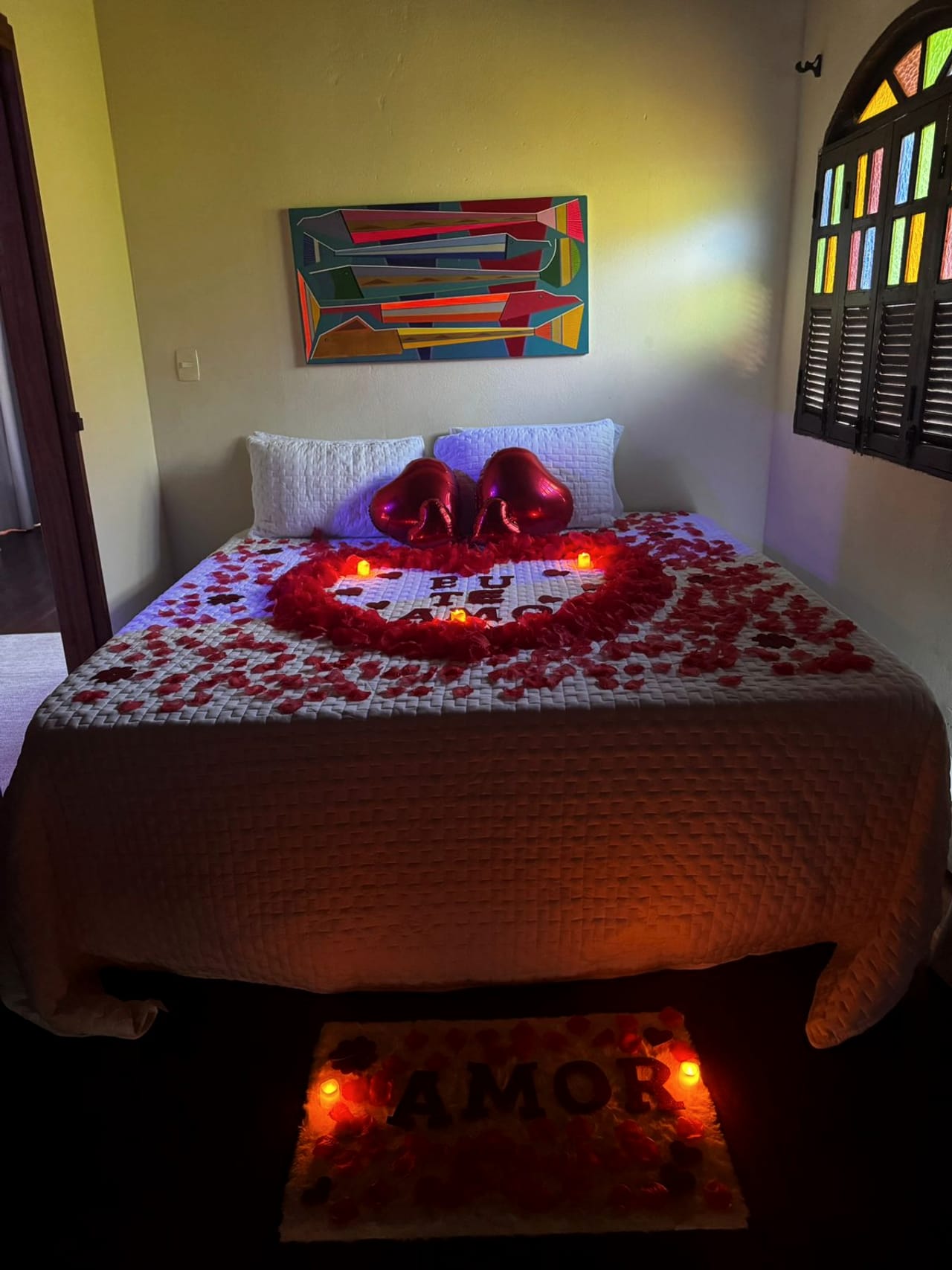 Cama decorada com pétalas vermelhas e velas