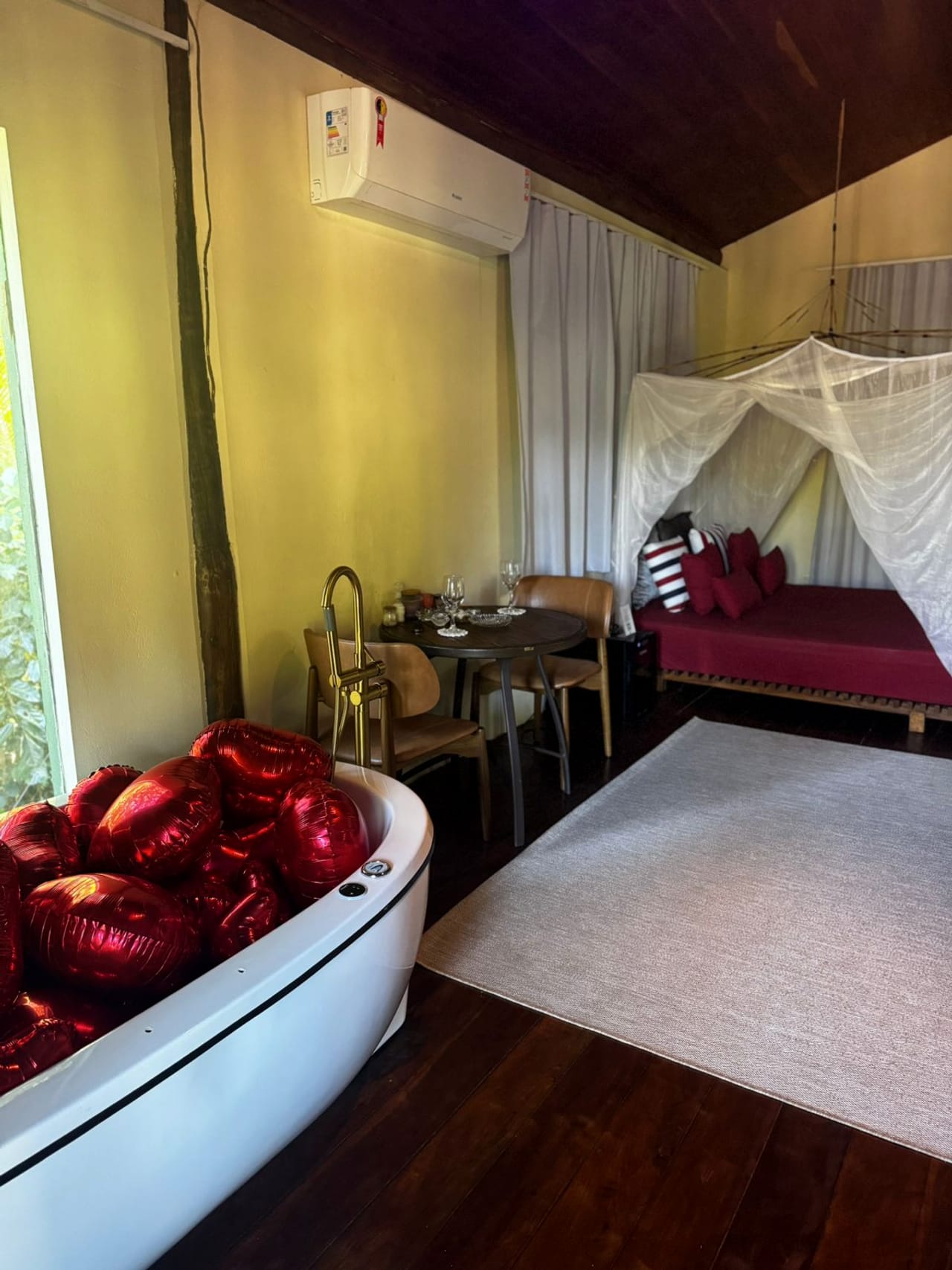 Jacuzzi decorada com balões vermelhos em forma de coração, ao lado da cama