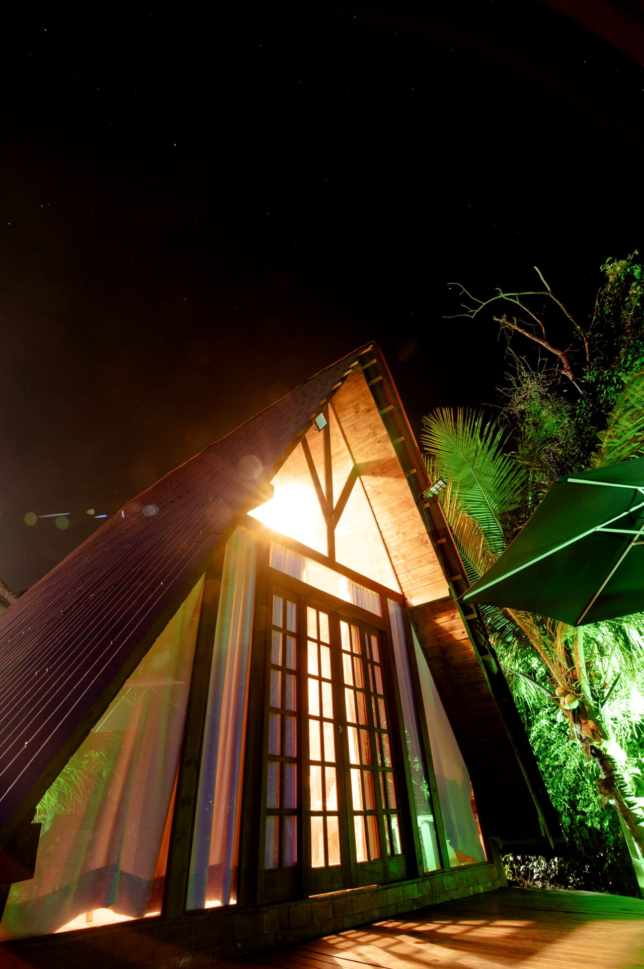 Cabana Esmeralda iluminada à noite entre as árvores