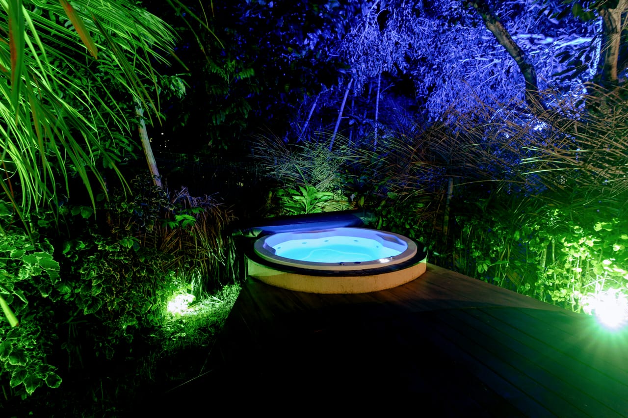 A jacuzzi acesa à noite, com a mata iluminada de azul
