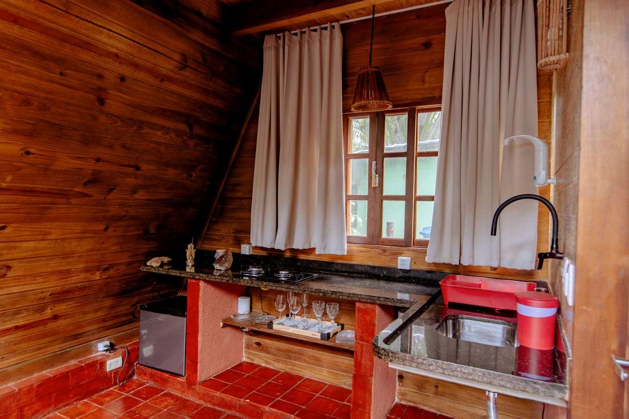 Bancada da cozinha em madeira com cooktop e janela para a mata