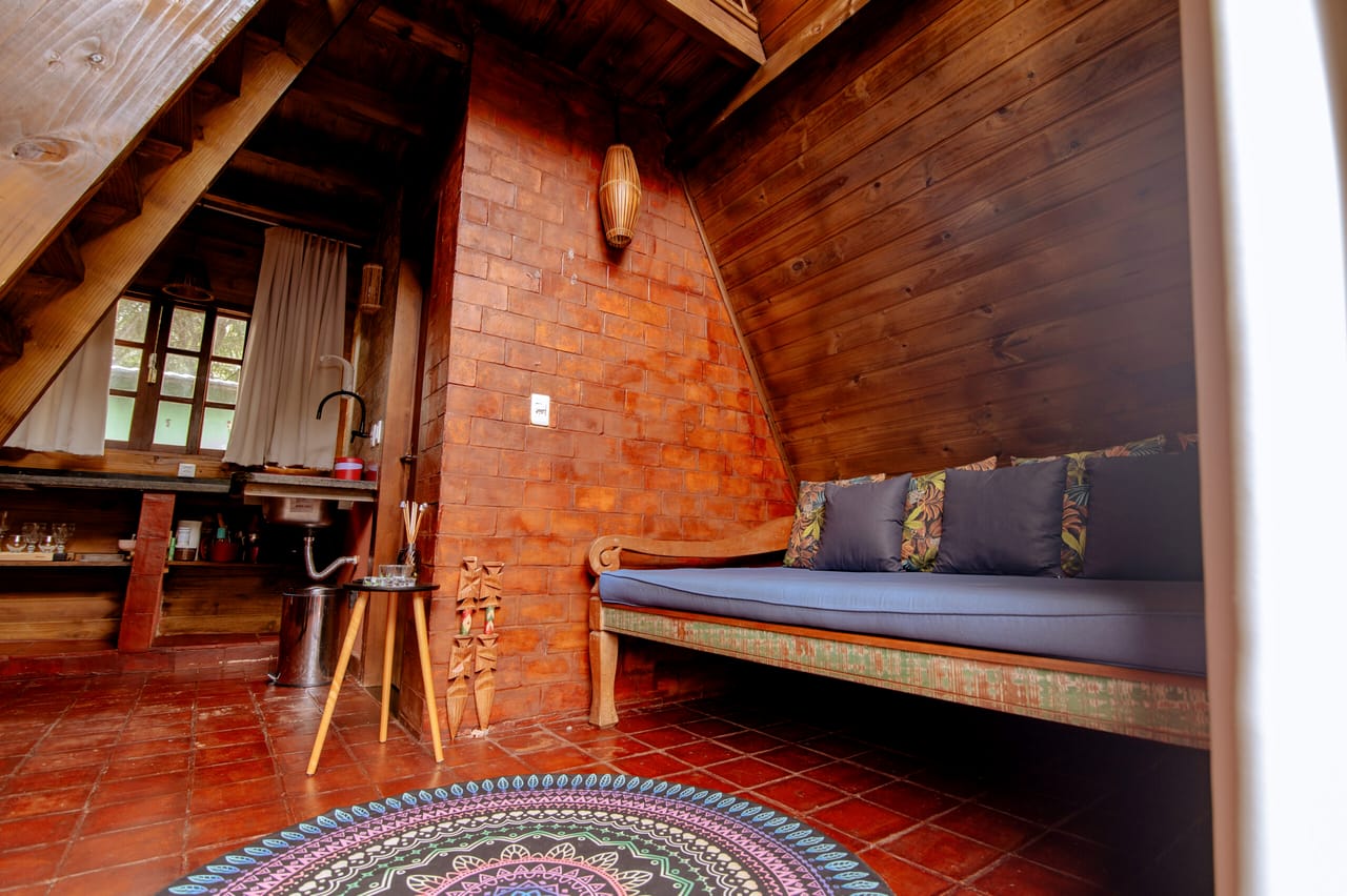 Sala da Cabana Rubi com sofá baixo e piso de tijolo