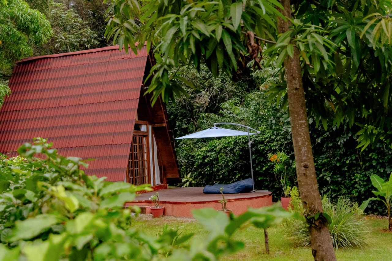 A Cabana Rubi entre as árvores, com guarda-sol aberto no deck