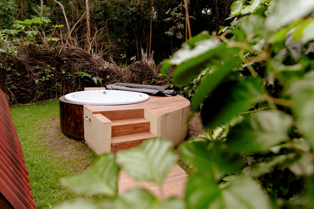 Jacuzzi de alvenaria no jardim, vista por entre as folhas