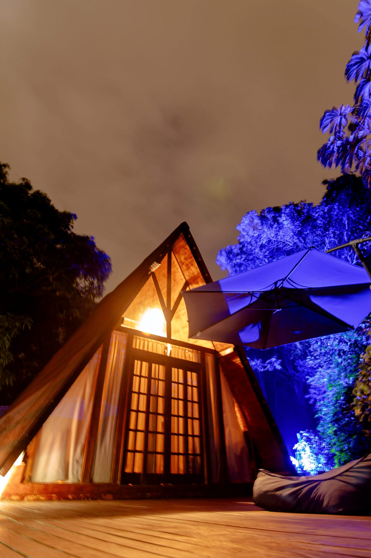 A cabana iluminada à noite, com a mata banhada de luz azul