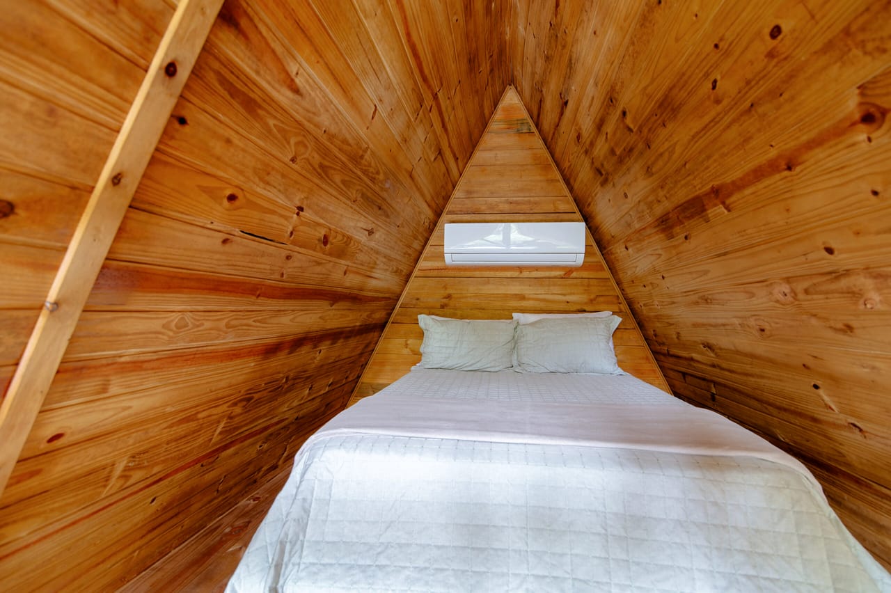 Cama no mezanino sob o telhado triangular de madeira