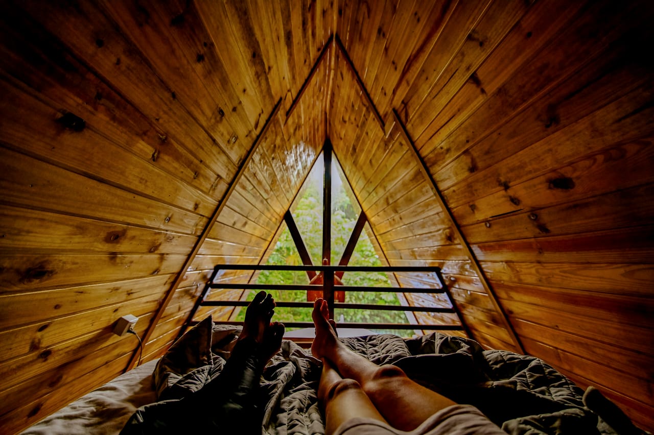Vista da cama para a janela triangular, com a mata do lado de fora