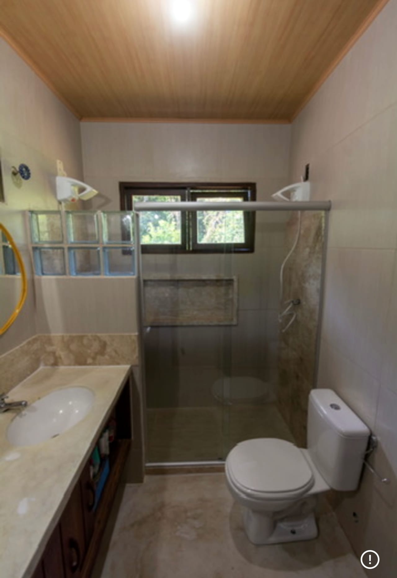 Banheiro com box de vidro e janela para o verde