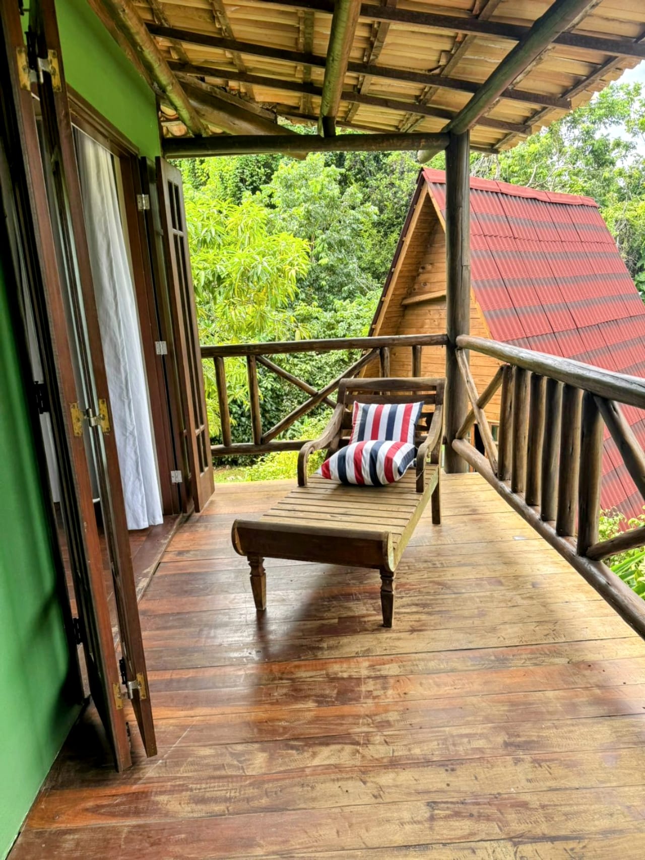 A varanda de cima, com espreguiçadeira e vista para as cabanas